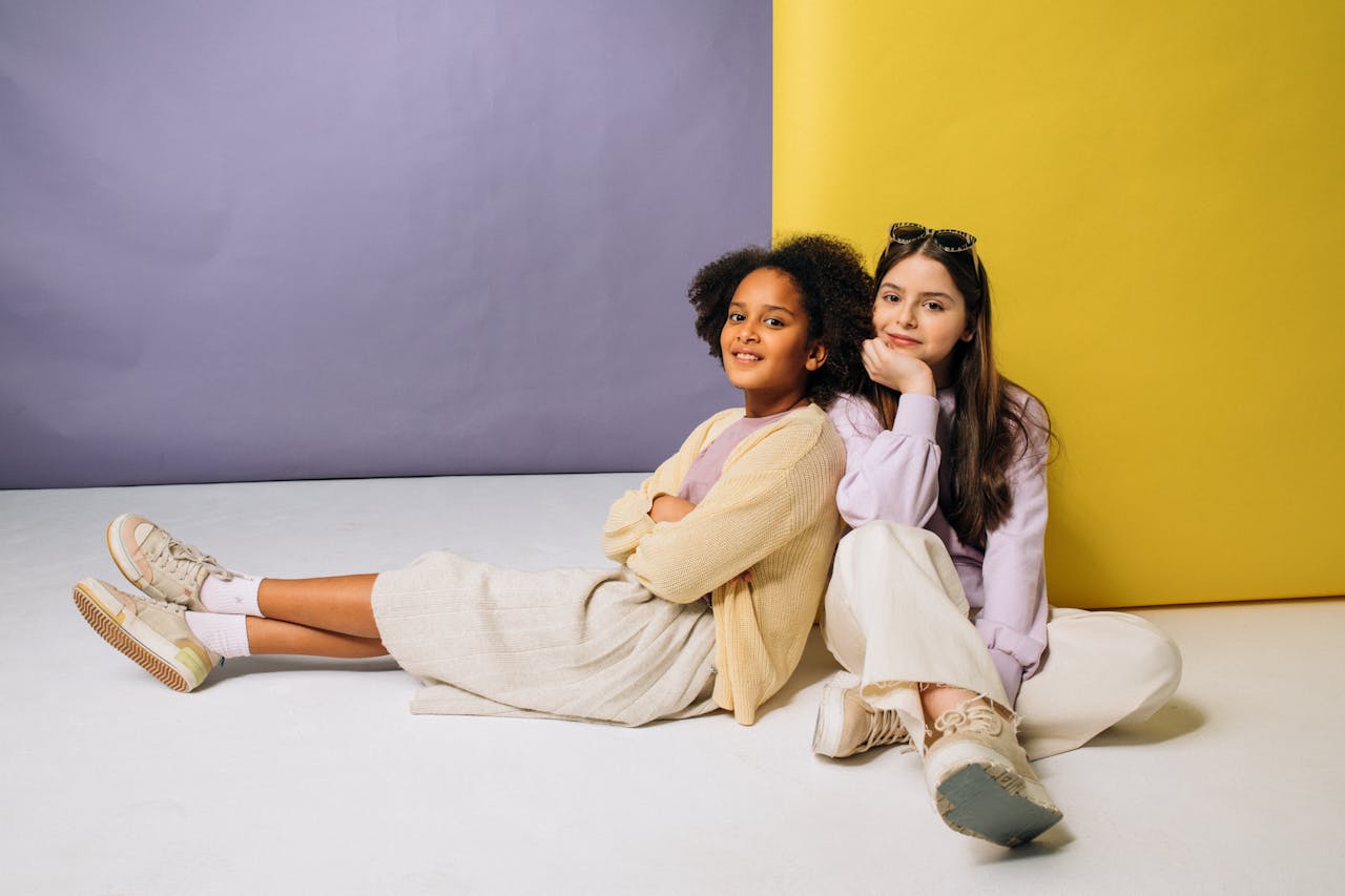 Two smiling girls relaxing against a vibrant backdrop, showcasing friendship.