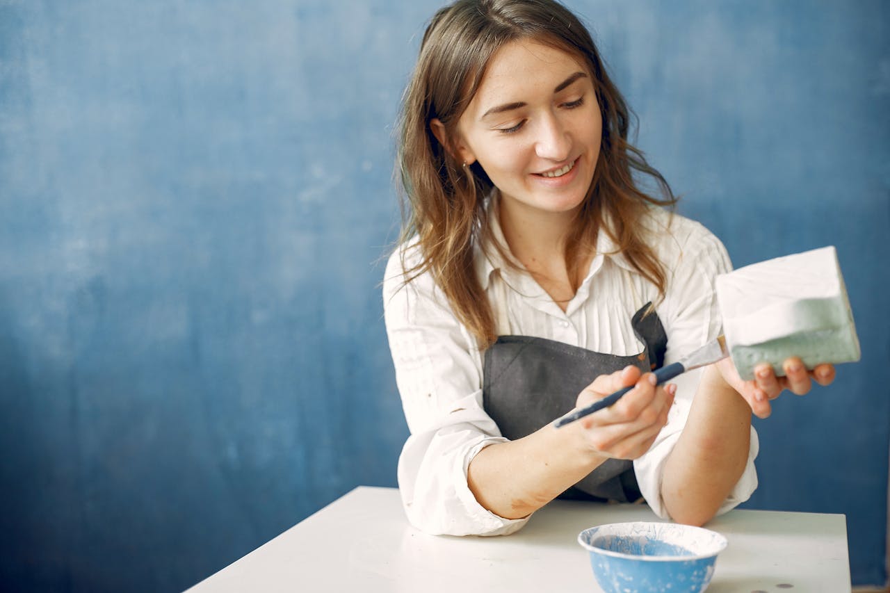 A young potter painting ceramics in a workshop, showcasing creativity and skill.