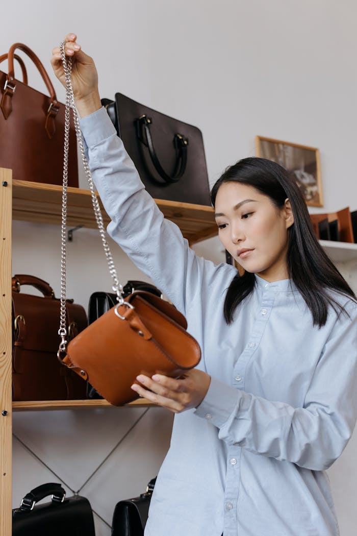 An adult woman examines a stylish leather shoulder bag in a fashion showroom.