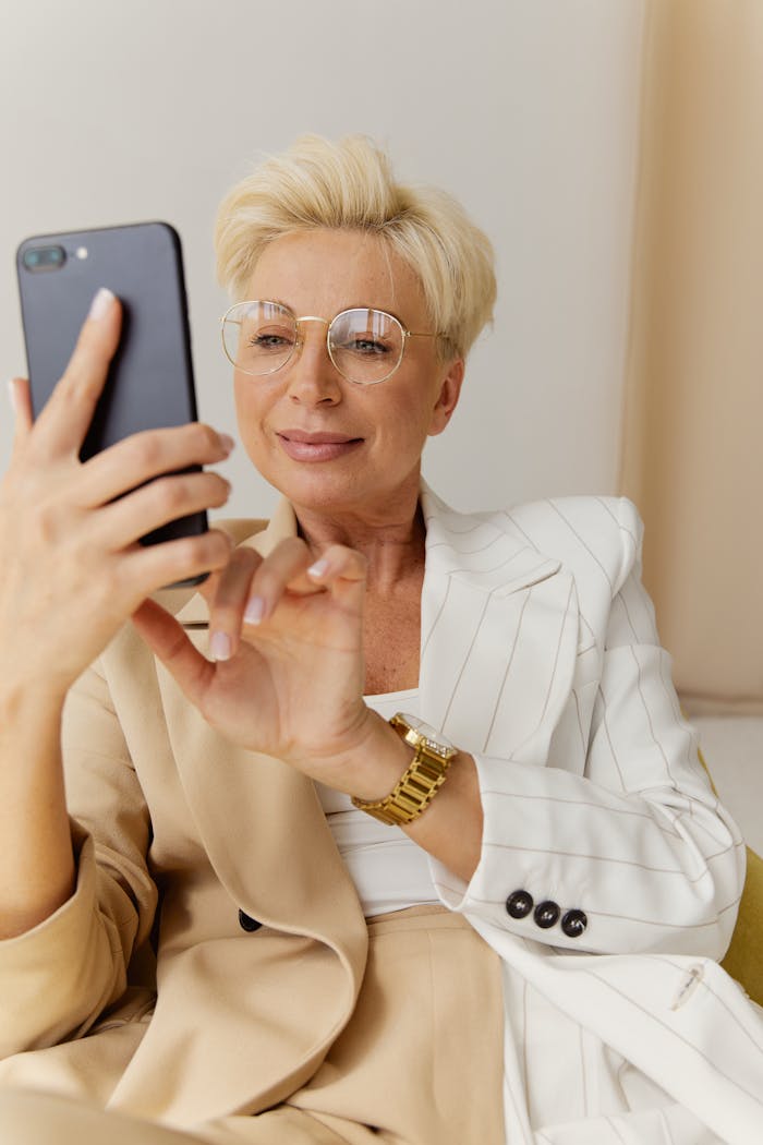 Elegant senior woman enjoying her smartphone experience indoors wearing eyeglasses.